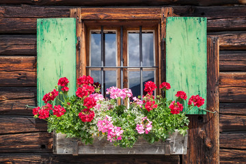 Fototapeta na wymiar Window of an old wooden cabin in the alps