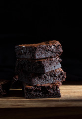 Chocolate brownie on the black background, side view, selective focu