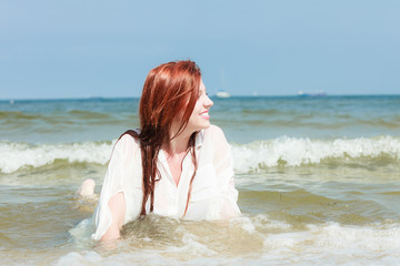 Sensual girl wet cloth in water on the coast.