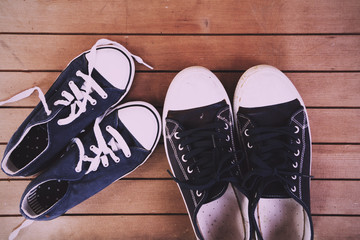 Old canvas shoes on a wooden floor Vintage Retro Filter.