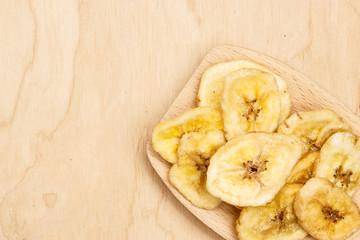 Heap of dried banana chips on wooden spoon