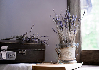 still life. vintage. old suitcase and sprigs of lavender on the background of old windows to the garden. lilac shades