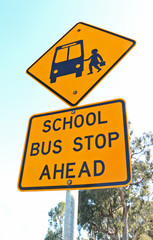 yellow and black school bus stop ahead sign and blue sky