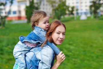 Mother with the child on his back outdoors in the summer