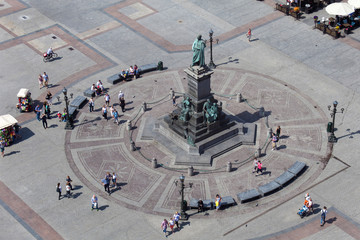 Fototapeta premium Adam Mickiewicz monument at the Main Market square with walking people. Aerial view from St. Mary Cathedral tower.