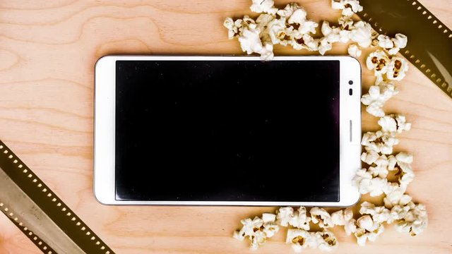 Tablet pc on wood with animated attributes of cinema. Visual metaphor for internet content - films and media on a mobile device.
