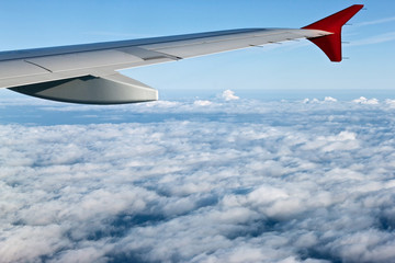 Obraz premium View from the airplane at the wing, white clouds and blue sky.