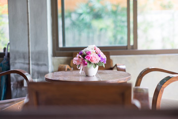 Beautiful flowers in vase on table in room. (old lens effect)