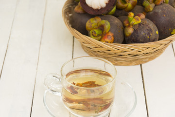 Mangosteen juice from herbs and mangoteen in the basket on wooden white background.Top view and zoom in