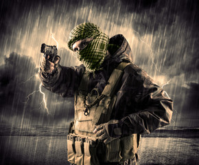 Dangerous armed terrorist with mask and gun in a thunderstorm wi