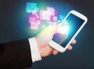 Hand holding smart phone with abstract glowing squares