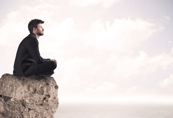 Business man sitting on stone edge