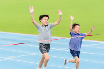 Young Asian boy running on blue track in the stadium