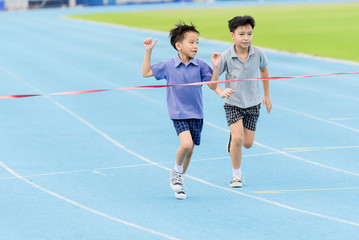Fototapeta premium Young Asian boy running on blue track in the stadium