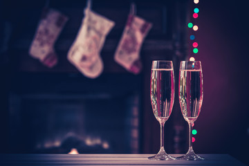 Two champagne glass on blurred background by the fireplace in the Christmas interior