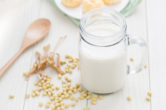 Soy milk in a glass , soybeans on a white table