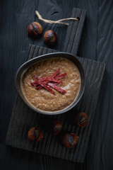Serving board with chestnut creamy soup, dark wooden setting