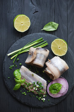 Stone slate tray with herring fillet, onion and lime, above view