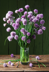 Bouquet of onion (chives) flowers in the vase on the wooden tabl