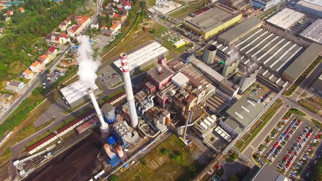 Camera flight over dustrial zone with fuming chimneys. Heavy industry from above. Steelworks and power plant in Pilsen, Czech Republic, European Union. 