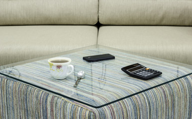 Cup of coffee, mobile phone and calculator on glass table. Simple workspace or coffee break in morning