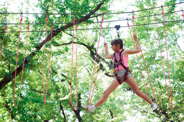 Naklejka na ściany i meble adventure climbing high wire park - hiking in the rope park girl
