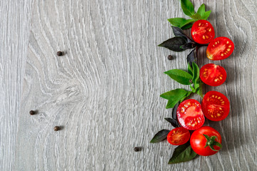 Cherry tomatoes and fresh basil on grey wooden  background. Frame. Copy space.