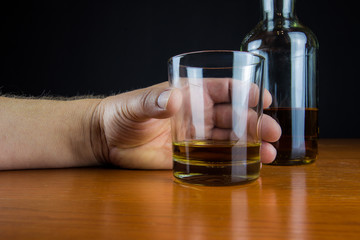 eine Hand greift nach einem Glas mit Alkohol