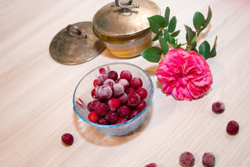 frozen cherry in a glass vase, honey and pink roses on wooden background