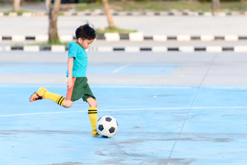 Boy play football on the blue concrete floor.