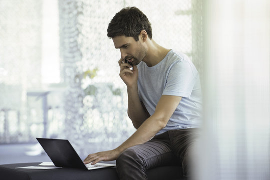 Man using laptop computer during phone call