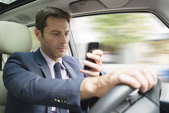 Businessman looking at smartphone in car