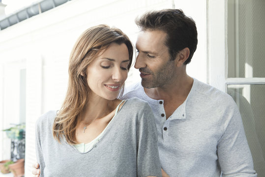 Smiling couple standing together near open window