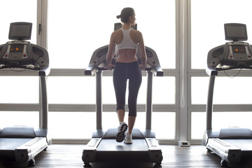 Rear view of woman exercising on treadmill in gym