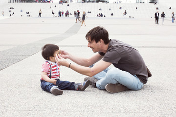 Father putting sunglasses on infant son outdoors