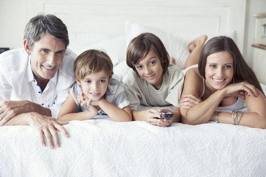 Family watching TV on bed, portrait
