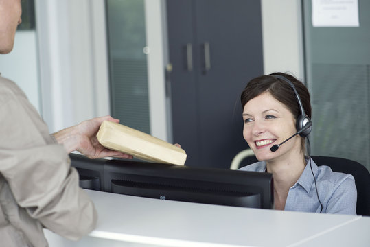 Receptionist receiving package from delivery person
