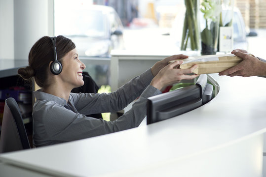 Receptionist accepting package from delivery person