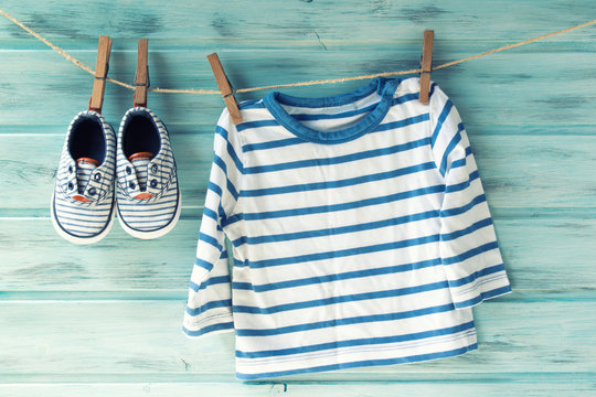 Baby boy striped shirt and baby shoes on a clothesline, vintage filter