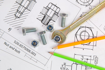 Wrench, pencil, bolts and nuts on background of engineering drawings. Science, mechanics and...
