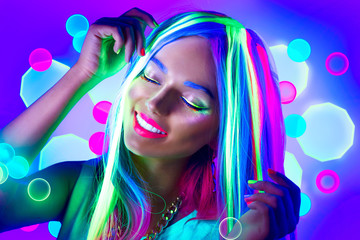 Young woman dancing in neon light. Beauty model girl with fluorescent make-up