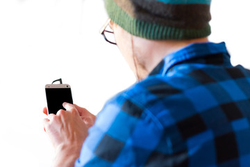 Junger Mann mit kariertem Hemd und Smartphone in der Hand, freigestellt