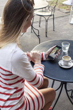 Young woman using multimedia smartphone at outdoor cafe