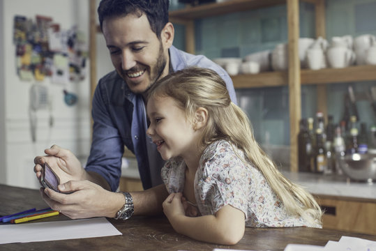 Father and daughter looking at smartphone together
