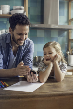 Father and daughter watch video streaming on smartphone together