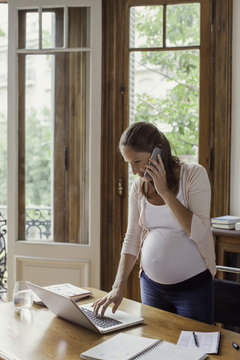 Woman using laptop computer and making phone call