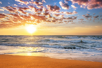 Obraz premium Colorful ocean beach sunrise with deep blue sky and sun rays.