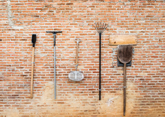 Agricultural equipment hanging on brick wall