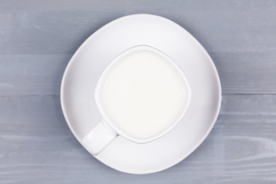 Top view of a white cup of milk on wood.