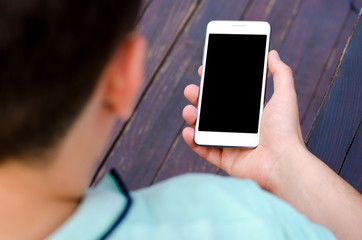White mobile phone holding a young hipster man in business shirt mint color on purple wooden background
